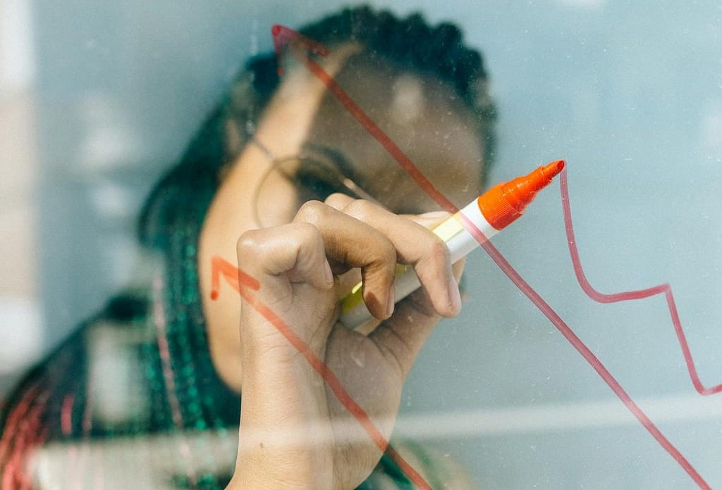 Seorang wanita sedang menggambar grafik progres yang mengarah ke atas.